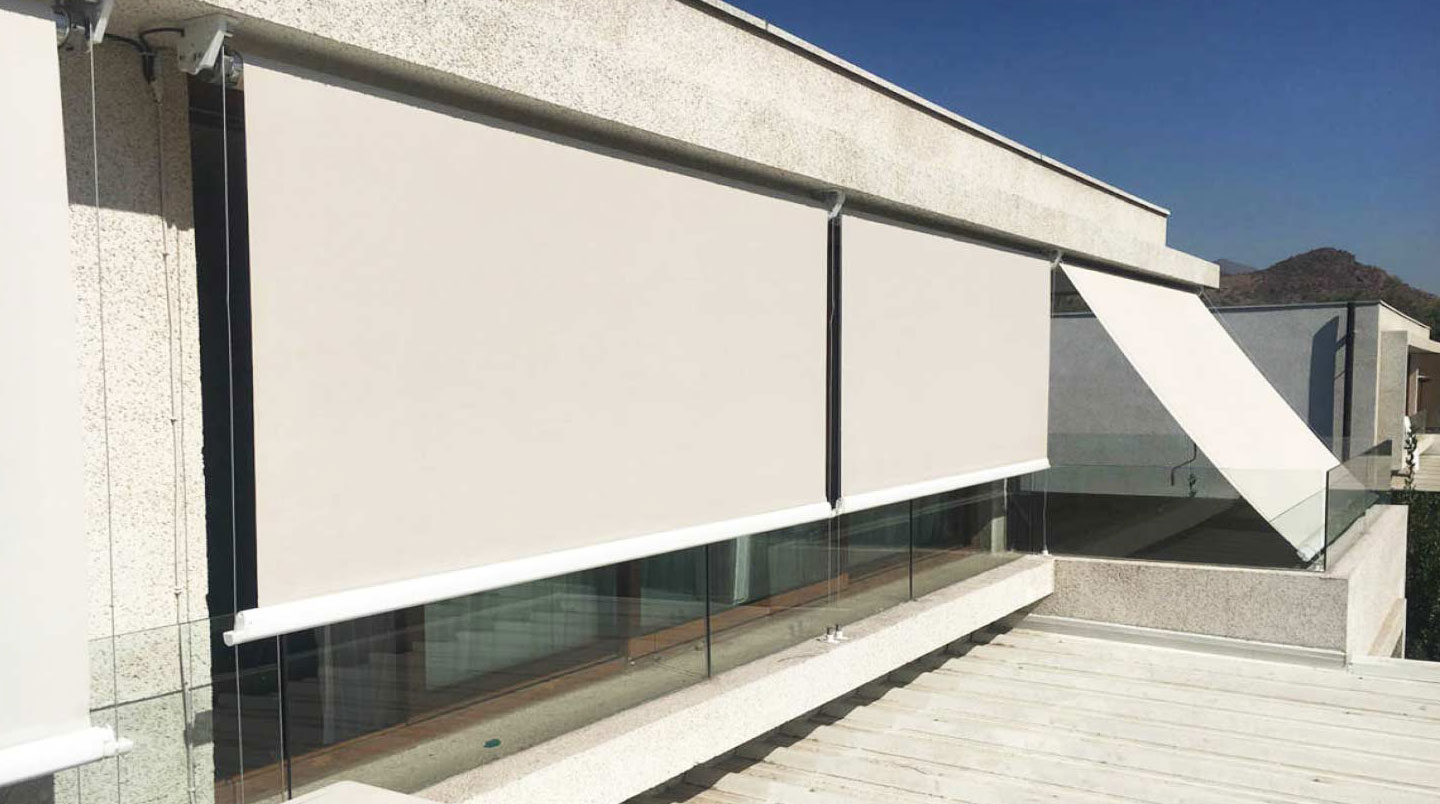 Persona vista de espaldas accionando manualmente toldo vertical con guías desde el interior de una vivienda junto a ventana